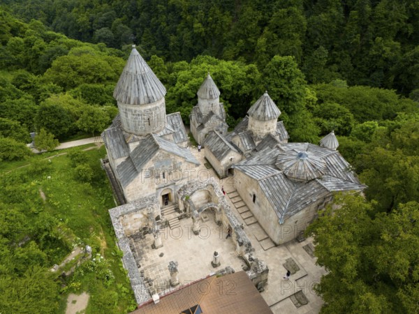Aerial view of a historic monastery with striking stone architecture, surrounded by forest, aerial view, Haghartsin Monastery, Hagarzin, Surp Astvatsatsin church on the left, Surp Stepanos and Surp Grigor churches and a gavit on the right, Tavush Province, Armenia