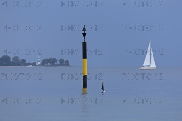 Black-yellow navigation mark, in the background lighthouse Bülk, sailing boat, Falckenstein, Kiel, Schleswig-Holstein, Germany