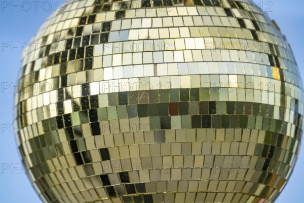 Golden disco ball, small mirrors, distributed like a mosaic, reflect light and create lighting effects in a room