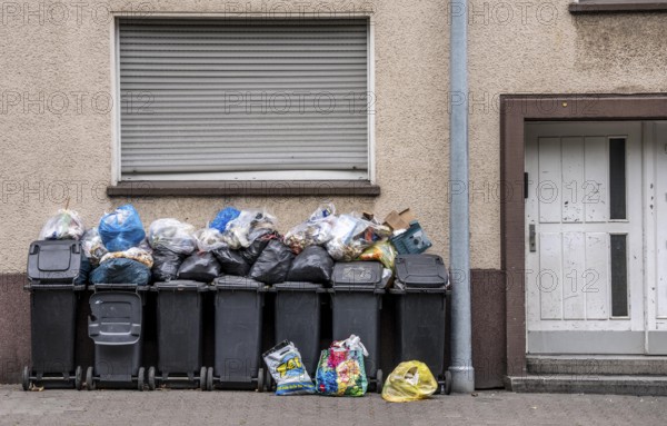 Overflowing rubbish bins in front of a residential building in Gelsenkirchen, North Rhine-Westphalia, Germany