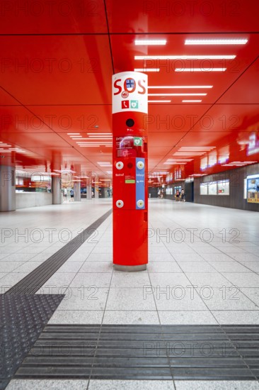 Empty area in the underground station with red design element and central information stand, Munich, Germany