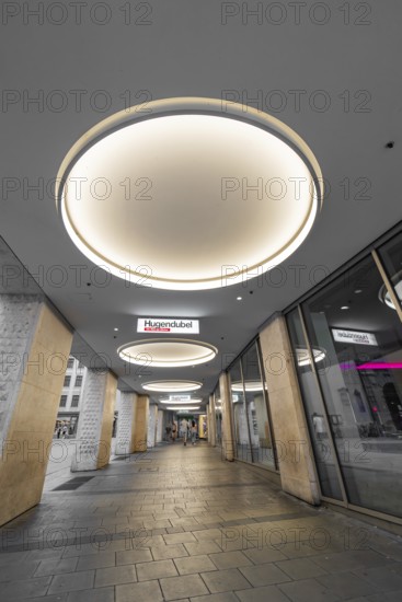 Modern shopping arcade with illuminated ceiling lights and shops, Munich, Germany
