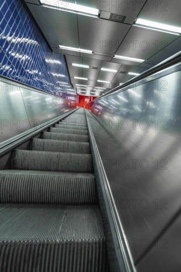 Steep escalator in the underground with silver and blue accents leading upwards, Munich, Germany