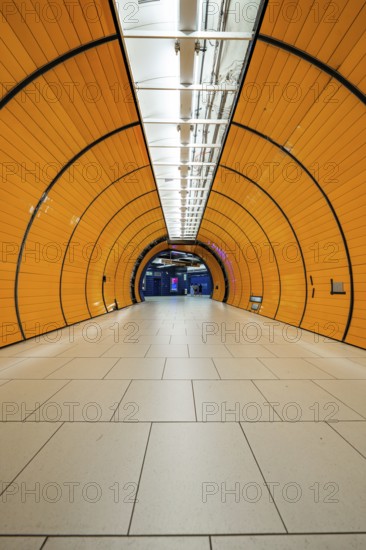 Long, illuminated underground railway tunnel in bright orange, leading into the distance, Marienplatz Munich, Germany