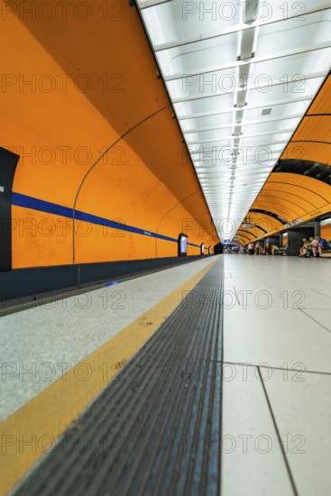 Long underground corridor with orange-coloured walls and strong lines leading into the depths, Marienplatz, Munich, Germany