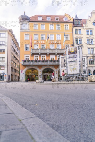 Historic city hotel with a striking orange-coloured façade and inviting entrance, Munich, Germany