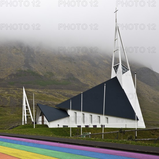 Street painted in the colours of the rainbow and the fish-shaped church designed by Hákon Hertervig, Ólafsvík, Snæfellsnes, Iceland