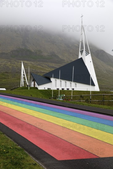 Street painted in the colours of the rainbow and the fish-shaped church designed by Hákon Hertervig, Ólafsvík, Snæfellsnes, Iceland
