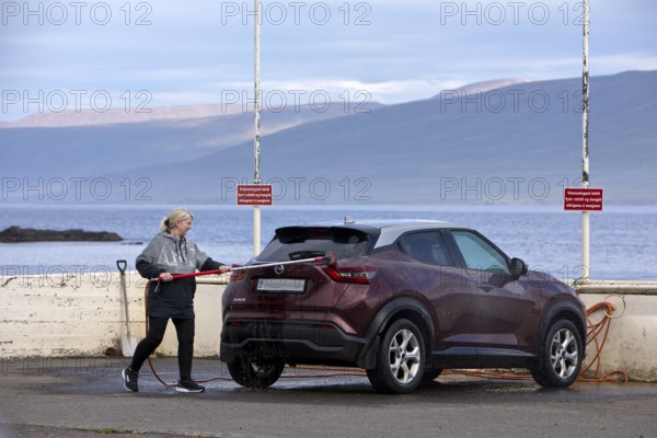 Washing the car with the free water brush at the petrol station by the Vopnafjördur fjord, East Iceland, Iceland