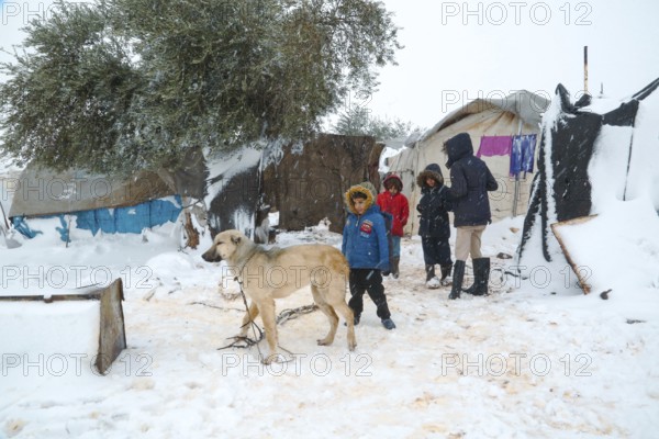 Displaced Syrian children playing in the snow near their tents inside a refugee camp during winter. Aleppo, Syria January 23, 2022, Aleppo, Syria