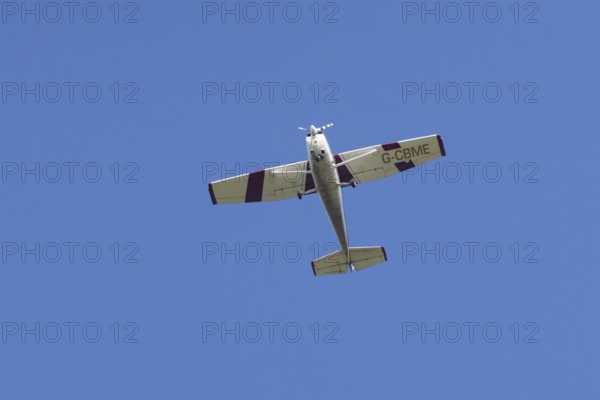Reims Cessna F172M Skyhawk light aircraft flying in a blue sky, England, United Kingdom