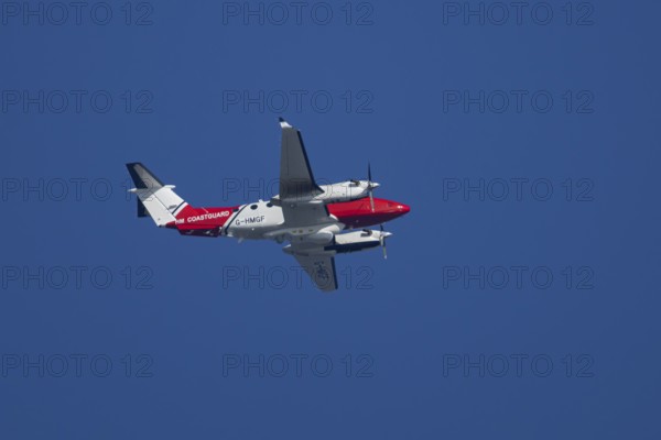 Beech King Air 350 light aircraft of the UK HM Coastguard flying in a blue sky, England, United Kingdom