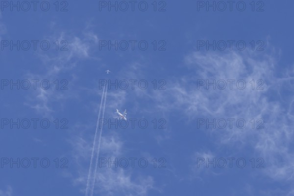 Two airliners Airbus A380 jet passenger aircraft of Emirates airlines and a Boeing 737 of Norweign Air flying in a blue sky, England, United Kingdom