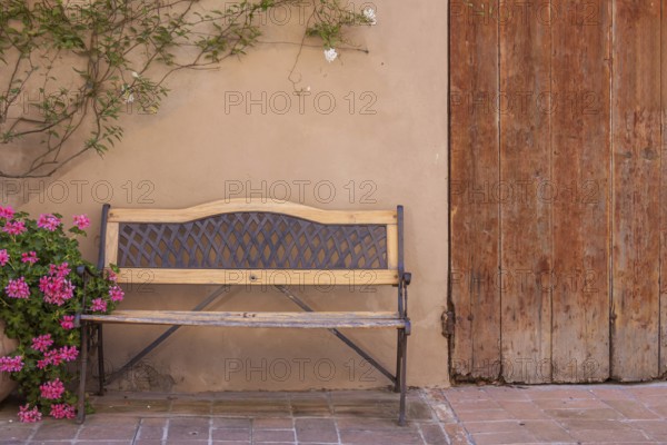 Bench in front of a house wall with flowers, Tuscany, Italy
