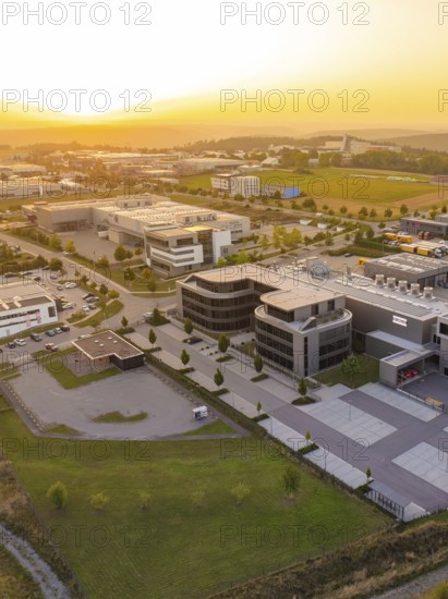 Modern commercial building with car park in a rural setting at sunset, industrial area Wolfsberg Nagold, district of Calw, Black Forest, Germany