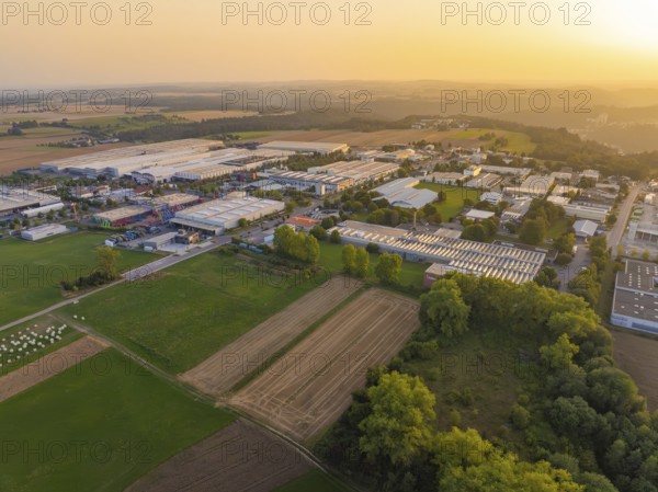 Industrial warehouses and fields in a vast rural landscape at sunset, Wolfsberg Nagold industrial area, Calw district, Black Forest, Germany