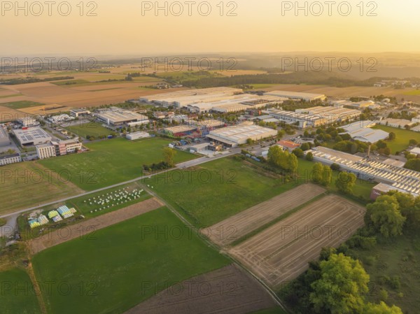 View of an industrial area surrounded by agricultural land in the evening light, Wolfsberg Nagold industrial area, Calw district, Black Forest, Germany