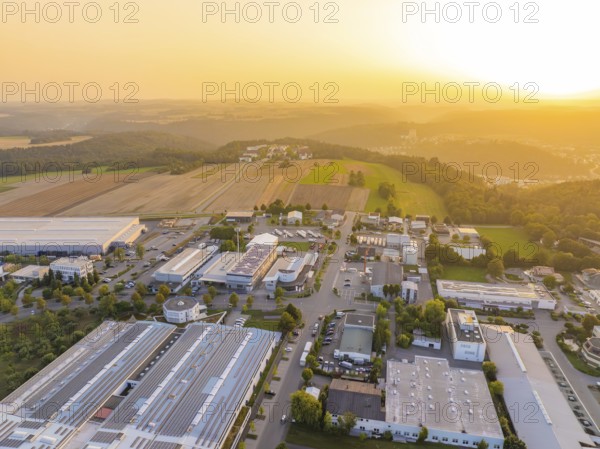 Industrial area in hilly landscape, surrounded by fields, at atmospheric sunset, industrial area Wolfsberg Nagold, district Calw, Black Forest, Germany