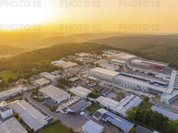 Large industrial complex at sunset, embedded in a hilly landscape with forests, industrial area Wolfsberg Nagold, district Calw, Black Forest, Germany