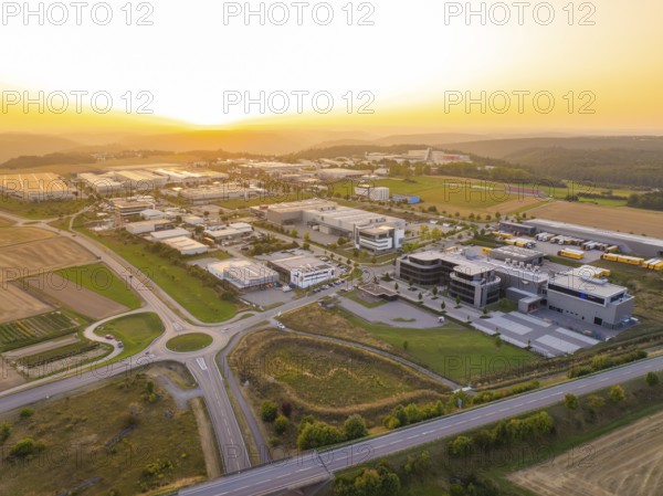 Wide view of an industrial area at sunset, surrounded by fields and forests, industrial area Wolfsberg Nagold, district Calw, Black Forest, Germany