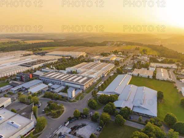 Industrial plants next to fields and forests in the warm light of the sunset, industrial area Wolfsberg Nagold, district Calw, Black Forest, Germany