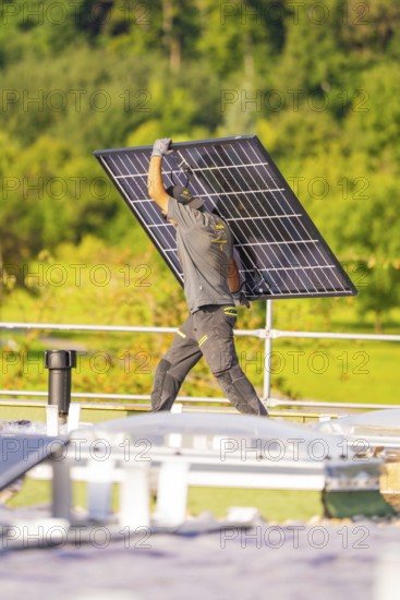 Person carrying a solar panel on a green roof, PV installation, commercial customers, new building, Pforzheim, Germany