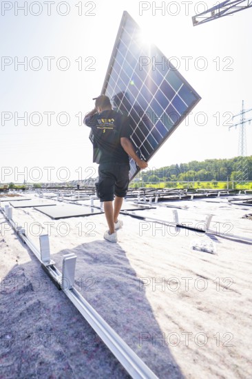 Workers carrying a solar panel on a roof in sunny weather, PV installation, commercial customers, new building, Pforzheim, Germany