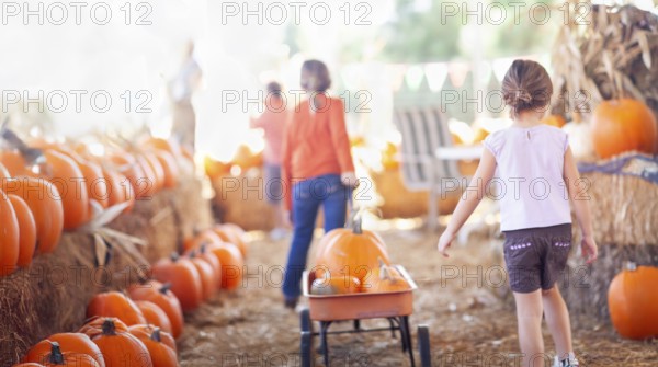Two young girls pulling their pumpkins in A wagon at a pumpkin patch on a fall day