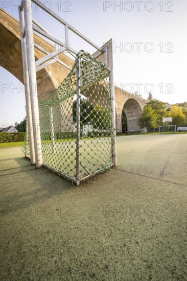 Sports goal with net on an asphalt pitch under a large bridge and trees, Nagold, Calw district, Black Forest, Germany