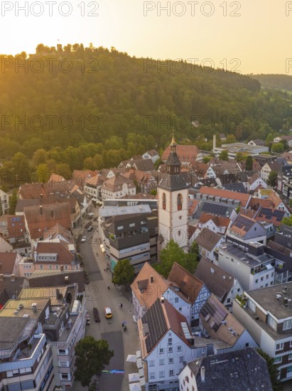 Church tower and town street at sunset, surrounded by hills and trees, Nagold, district of Calw, Black Forest, Germany