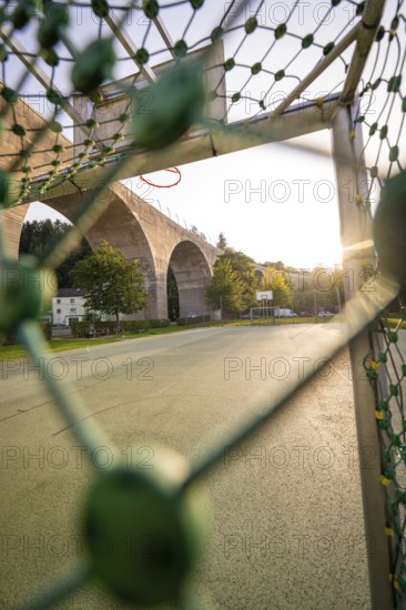 View through a basketball net onto a stone bridge in the morning light, Nagold, district of Calw, Black Forest, Germany