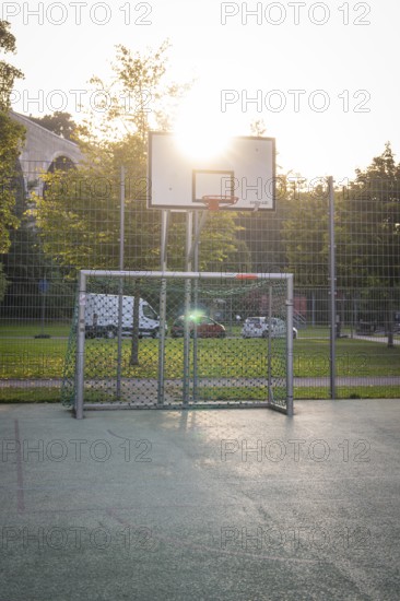 An outdoor basketball court with a basket and sunlight in the background, Nagold, district of Calw, Black Forest, Germany