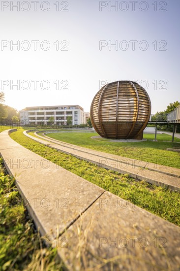 Wooden sculpture next to a modern building in the sunshine on a green lawn, Nagold, district of Calw, Black Forest, Germany