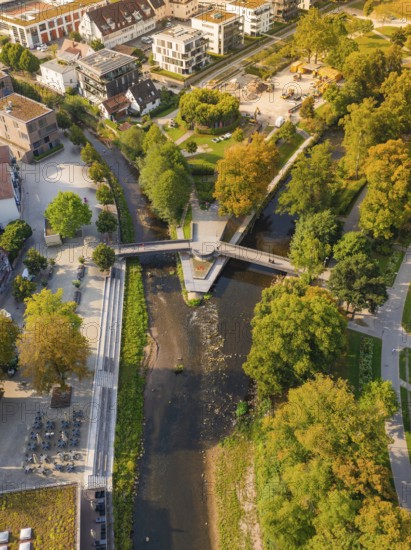 River with bridge in an urban park, surrounded by autumnal trees and buildings, Nagold, district of Calw, Black Forest, Germany