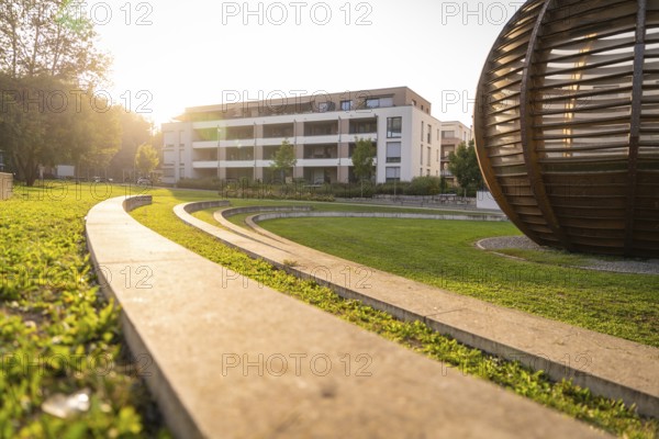 Modern park landscape with curved paths and a large building in the evening light, Nagold, district of Calw, Black Forest, Germany
