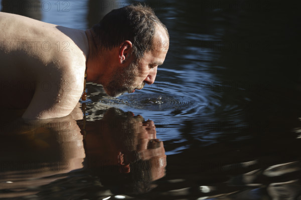 Man in the water during body care while travelling, Müritz National Park, Mecklenburg-Western Pomerania, Germany