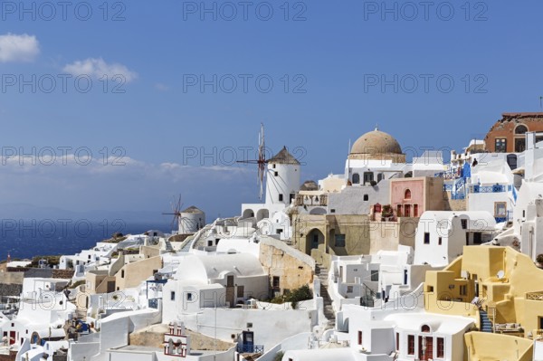 White and colourfully painted holiday homes on a steep slope, windmills, Cumulus, view of Oia, Thira, Santorini, Cyclades, Greece
