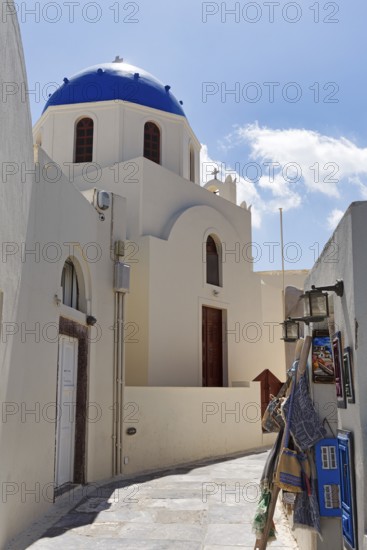 Orthodox church with blue dome in a narrow alley, shopping in the old town, Oia, Thira, Santorini, Cyclades, Greece