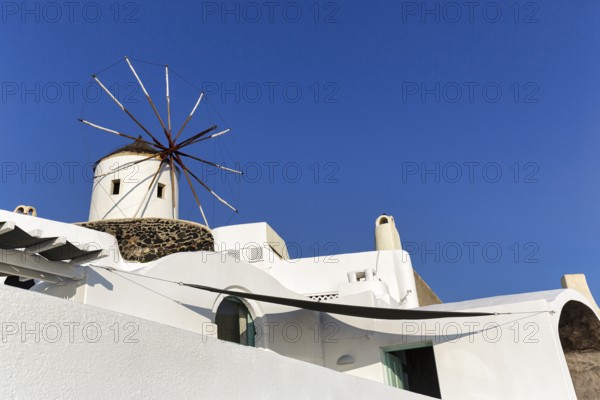 White windmill, typical holiday home, blue sky, sunny weather, text free space, Oia, Thira, Santorini, Cyclades, Greece