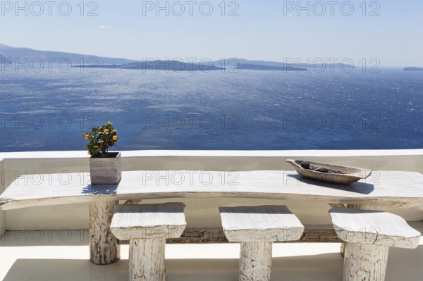 Wooden table on a white terrace by the sea, view of the caldera, Oia, Thira, Santorini, Cyclades, Greece