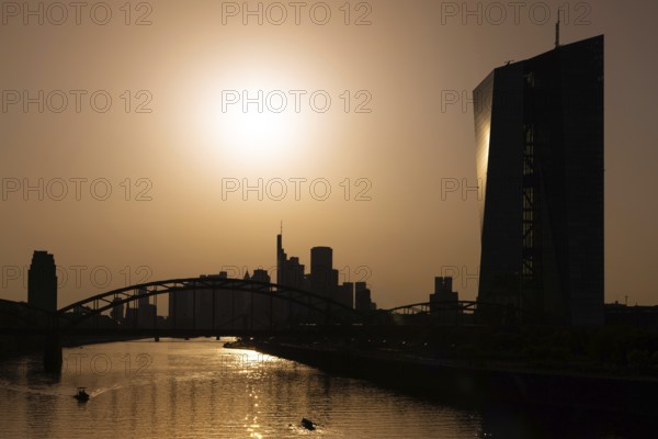 The sun is high above the European Central Bank (ECB) and the Frankfurt banking skyline, Frankfurt am Main, Hesse, Germany