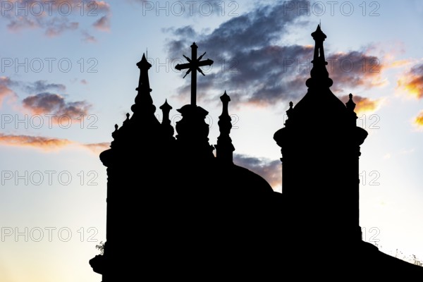 Silhouette of the towers and crucifix of an old baroque church in Ouro Preto during sunset