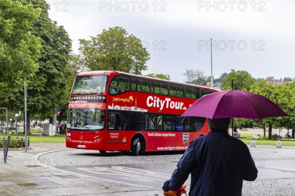 Stuttgart city tour. City tour in a red double-decker in rainy weather at Schlossplatz. City view of Stuttgart, Baden-Württemberg, Germany