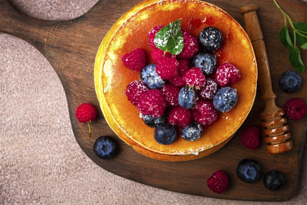 Breakfast, pancakes with berries and honey, top view, homemade, no people, on a wooden background