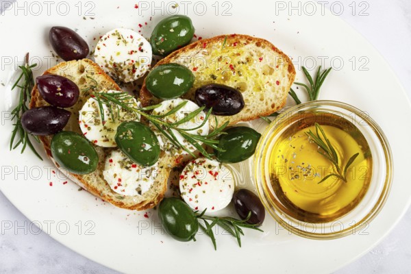 A plate with a snack, ciabatta bread with cheese and olives, olive oil, spices and herbs, top view, no people