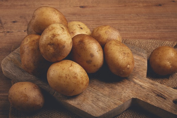 Raw potatoes, scattered on a chopping board, close-up, no people