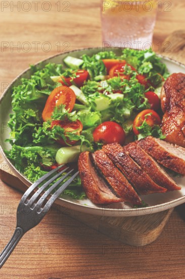 Delicious grilled duck breast served with fresh garden salad and cherry tomatoes at a rustic dining table