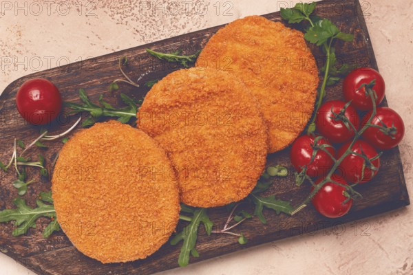 Crispy fried fish cutlets, fish burgers, on a wooden chopping board, with arugula and cherry tomatoes, homemade, no people