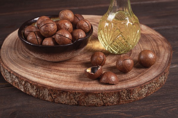 Bottle of macadamia oil, on a wooden board, with macadamia nuts, wooden background, selective focus, no people