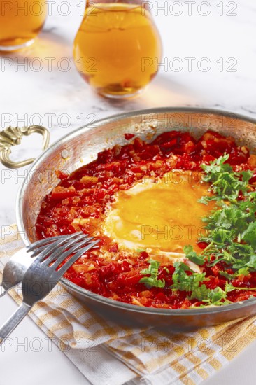 Traditional Turkish dish, scrambled eggs with tomatoes, Menemen, with herbs, in a frying pan, close-up, no people